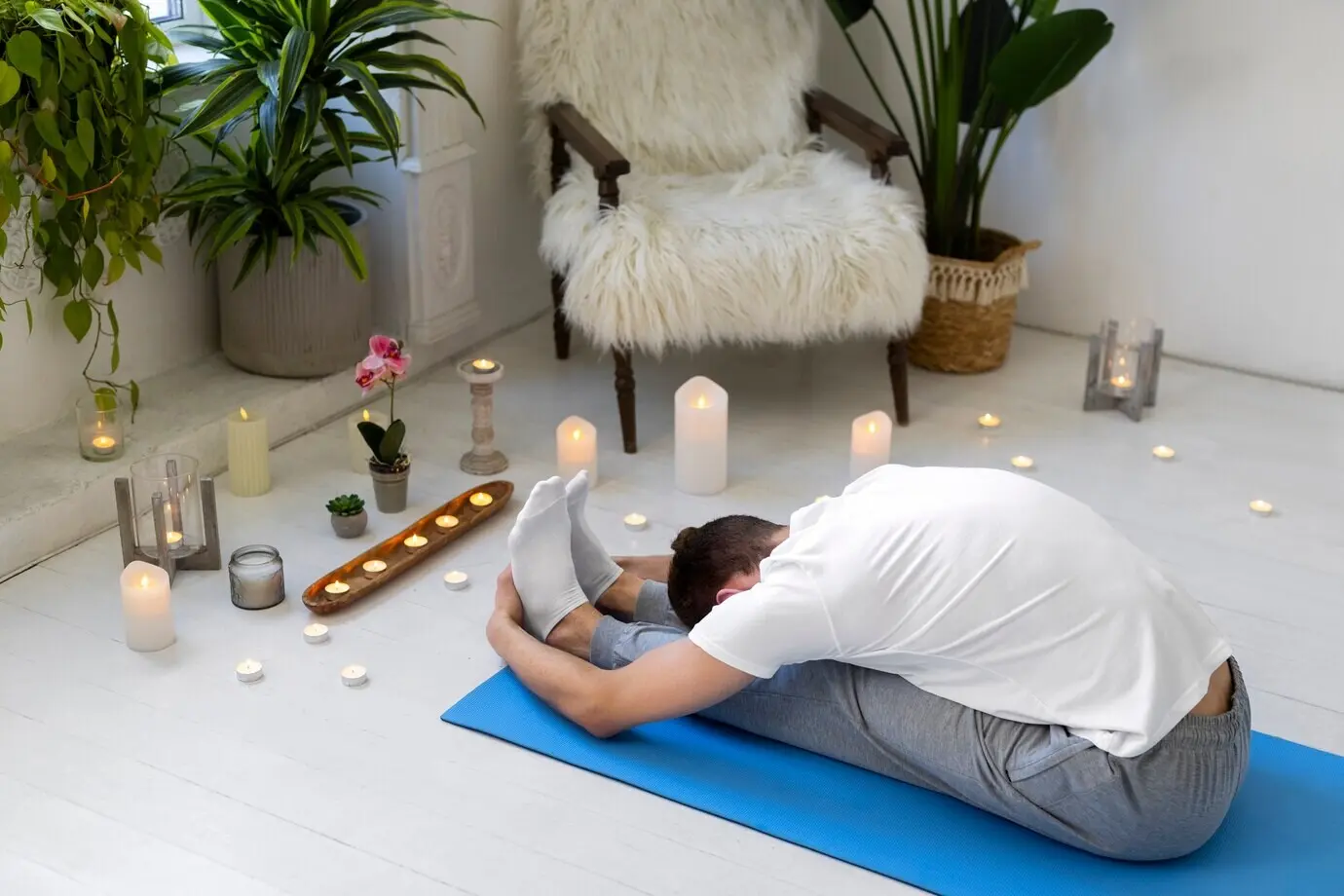 Кадр в полный рост мужчины, занимающегося йогой на коврике.