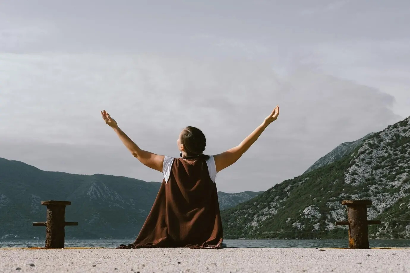 Молодая женщина на пирсе на фоне черногорской бухты.